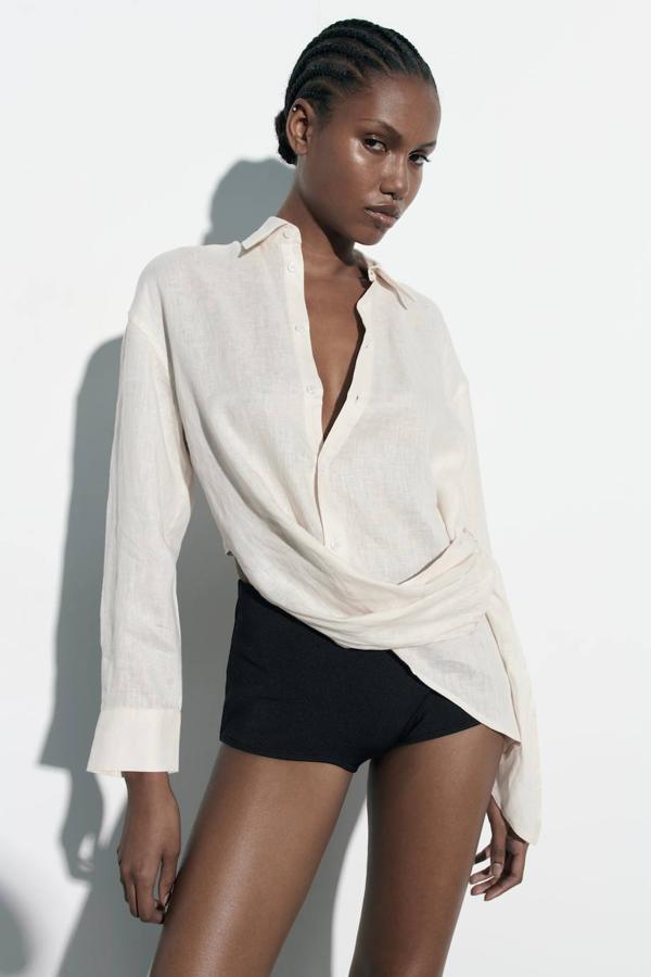 Camisa de lino con cuello solapa, manga larga, cierre de botones, detalle drapeado y bajo asimétrico, en crudo, de Zara. Cómprala a 29,95 euros.