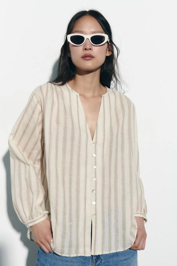 Camisa de lino con cuello redondo, escote de pico, manga larga, cierre de botones y print de rayas en crudo y marrón, de Zara. Hazte con ella por 25,95 euros.