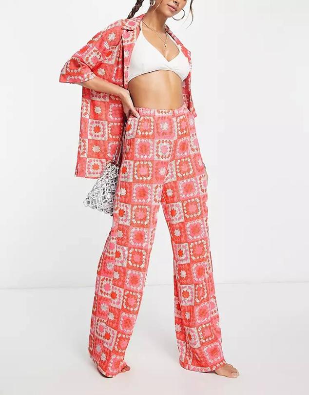 Pantalón de crochet con tiro alto, cintura elástica, perneras anchas y estampado de cuadros bicolor en rosa y naranja, de Damson Madder. Te costará 94,99 euros, en Asos.
