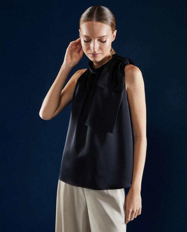 Top con corte fluido, manga sisa y cuello halter con maxi lazo, tono negro, de Woman El Corte Inglés. Lo encontrarás por 79,99 euros.