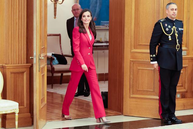 Si tuviéramos que decir cuál es el look favorito de la reina Letizia, este sería, sin duda, el traje de chaqueta y pantalón. Y sí, también tiene su versión en rosa fucsia. Y lo ha combinado con un top de encaje blanco y zapatos de tacón cómodo.