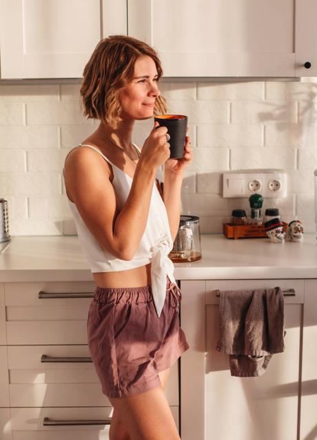Imagen - Mujer tomando una taza de infusión de pie en la cocina / Foto de Anna Alexes en Pexels