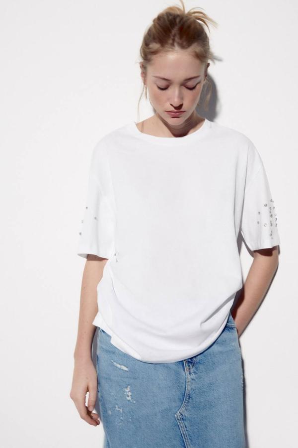 Camisa básica oversize con cuello redondo, manga corta y detalle de joyas, color blando. Te costará 15,95 euros.