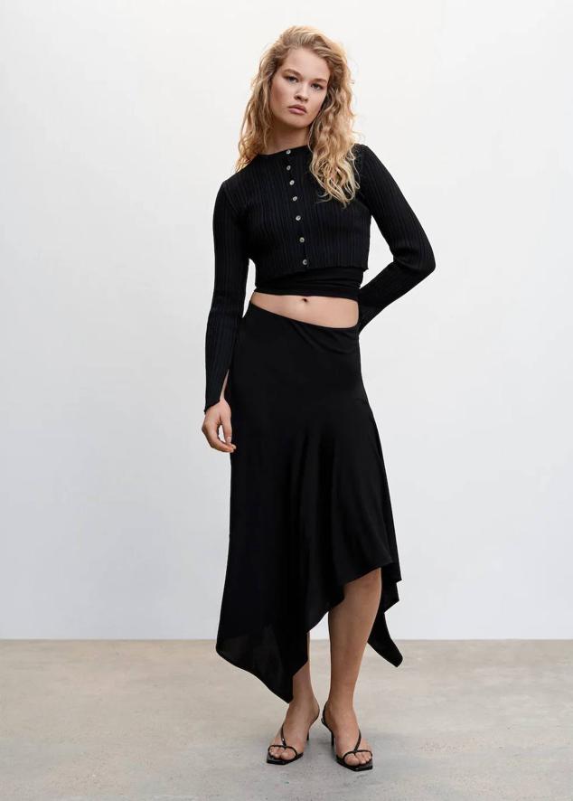 Falda midi en tejido fluido con tiro alto, cintura elástica y bajo asimétrico, color negro, de Mango. Te costará 35,99 euros.