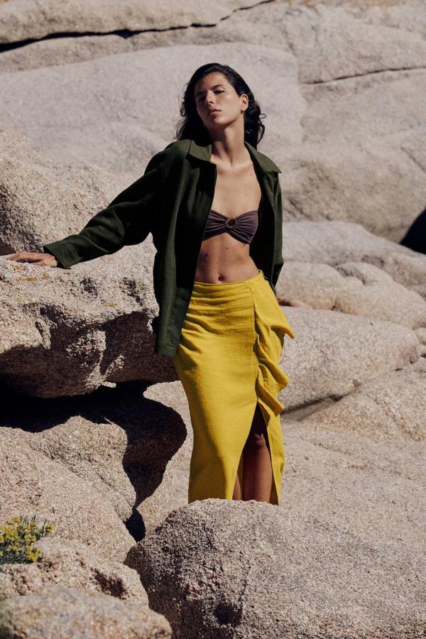 Falda midi en tejido de lino con detalle de volantes y abertura en el bajo, tono mostaza, de Zara. Hazte con ella por 25,95 euros.