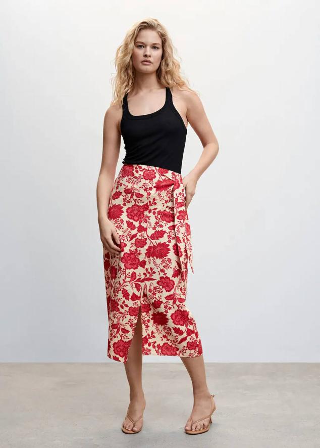 Falda midi cruzada con tiro alto, cierre de lazada y floral print, en crudo y rojo, de Mango. Está disponible a 29,99 euros.