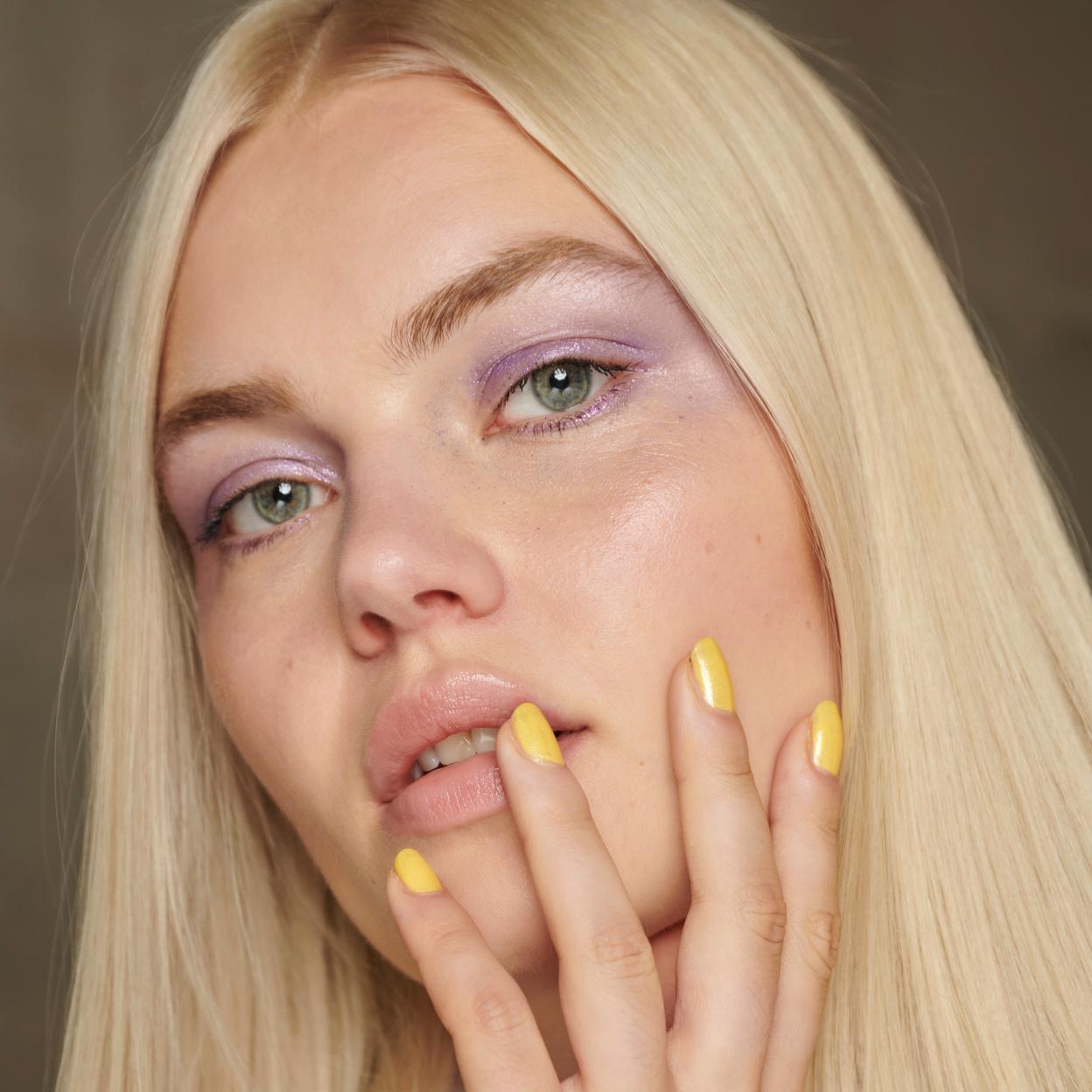 Una mujer con las uñas cuidadas en colro amarillo.