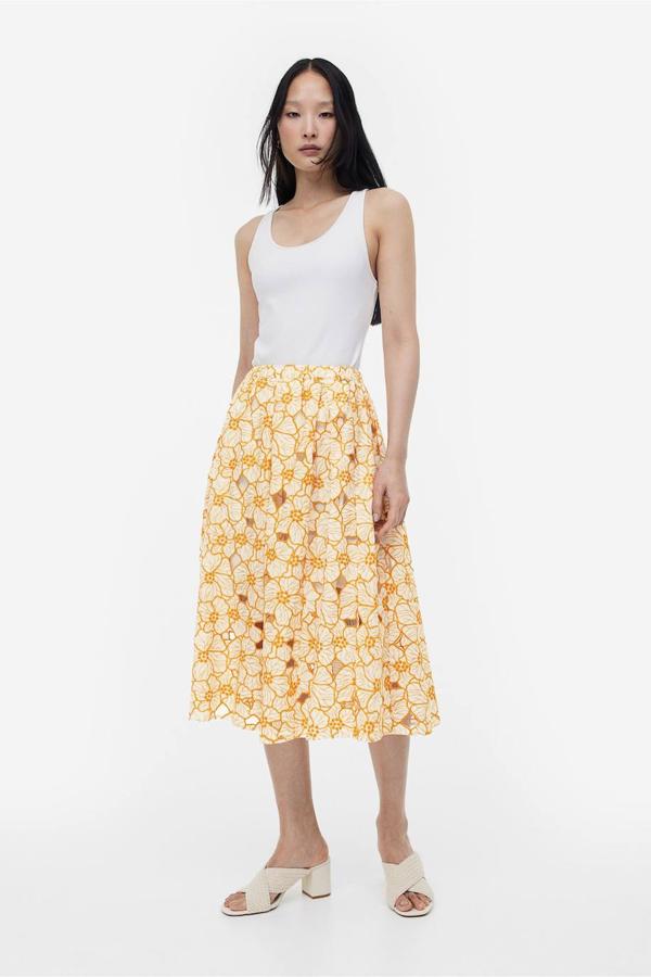 Falda midi en tejido de algodón con bordado inglés, tiro alto, volumen y vuelo, en floral print amarillo, de H&M. Cómprala a 59,99 euros.