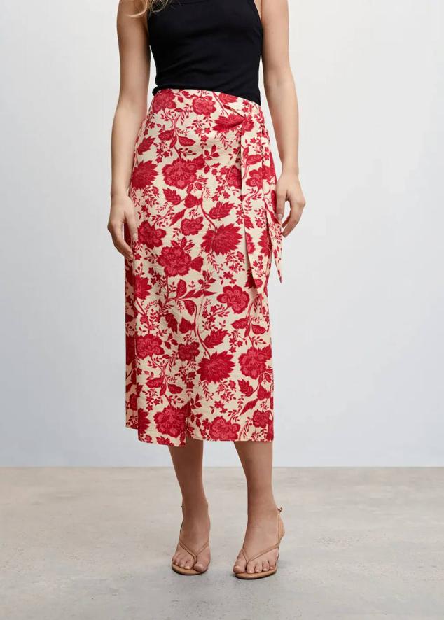 Falda midi tipo pareo con tiro alto, abertura y detalle de lazada, en estampado floral tonos crudo y rojo, de Mango. Su precio es de 29,99 euros.