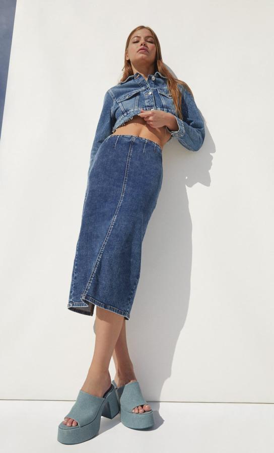La falda midi vaquera es la prenda tendencia del momento. Y nos encanta cómo han combinado este modelo que cuesta 25,99 euros: chaqueta croipped y sandalias de tacón con plataforma.