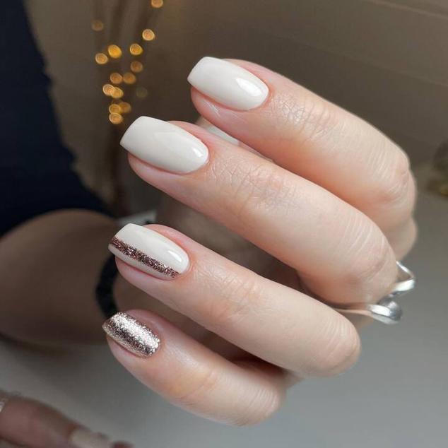 Si quieres darles un toque brillante y glamuroso a tus uñas blancas, lo más sencillo y con mejor acabado es usar purpurina. Para hacer este diseño, pinta las uñas con esmalte blanco. Y, dependiendo del modelo que quieras, puedes poner una o dos uñas con un esmalte glitter opaco. También está la opción de realizar líneas con purpurina en el centro de la uña. O, disponer el esmalte brillante solo en las puntas o la parte más cercana a las cutículas.