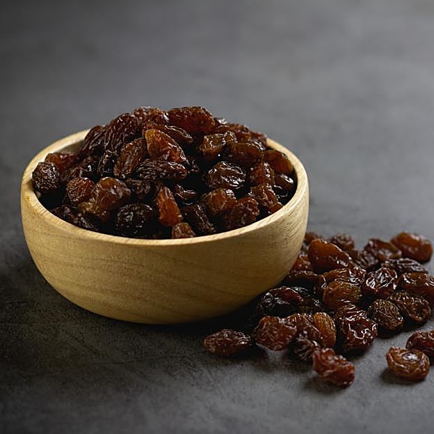 Uvas pasas en un recipiente sobre la mesa 