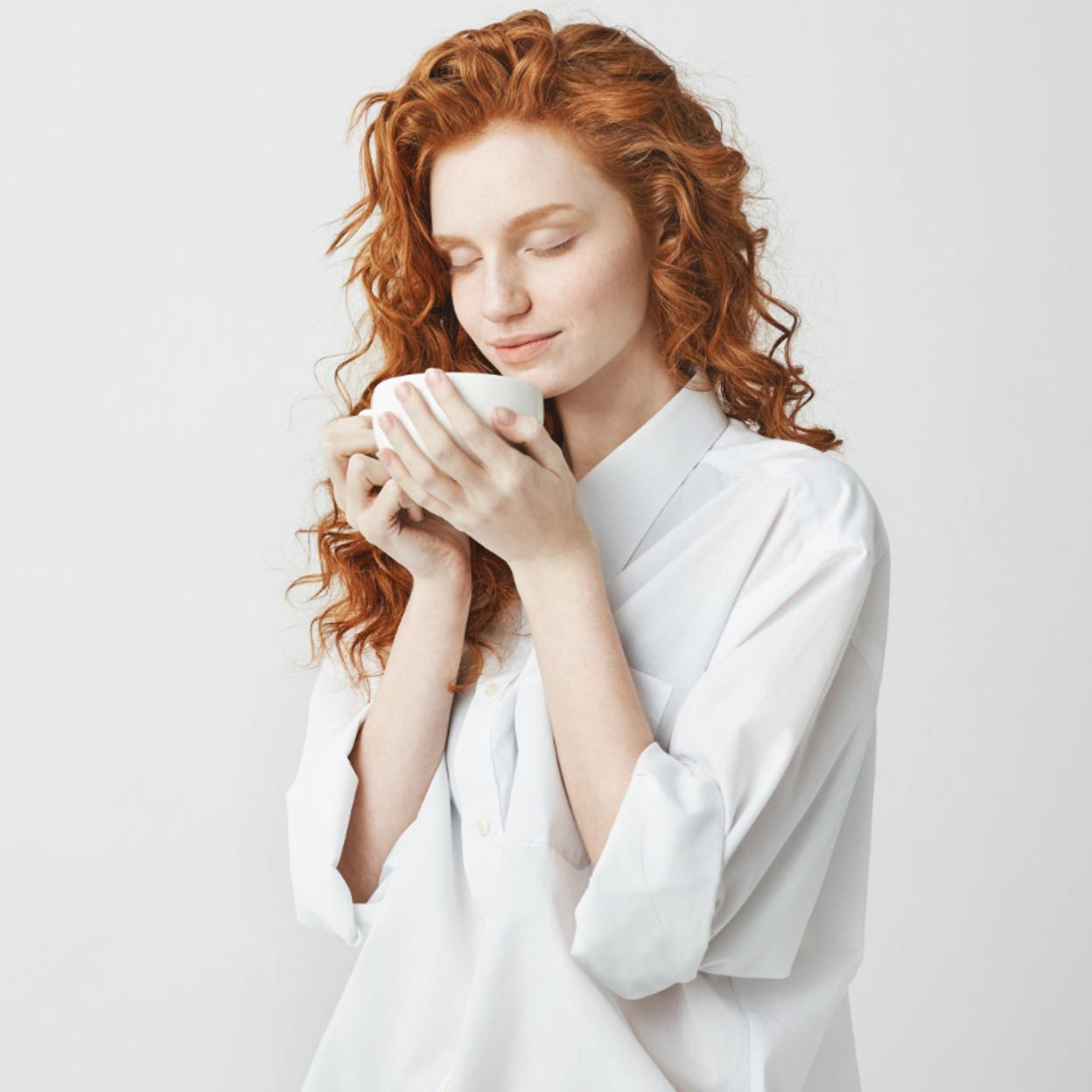 Mujer pelirroja tomando una infusión. 