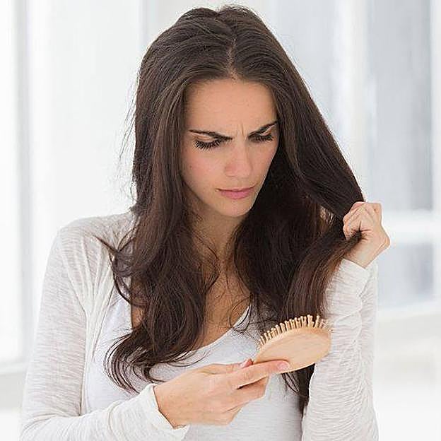 Mujer comprobando la pérdida de pelo en el cepillo
