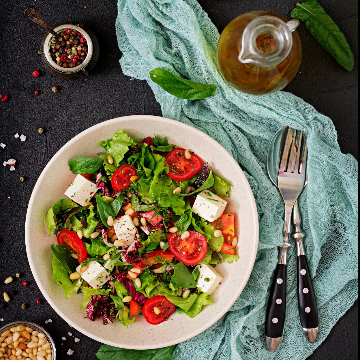 Ensalada con espinacas, tomate, queso feta, lechuga y piñones. 