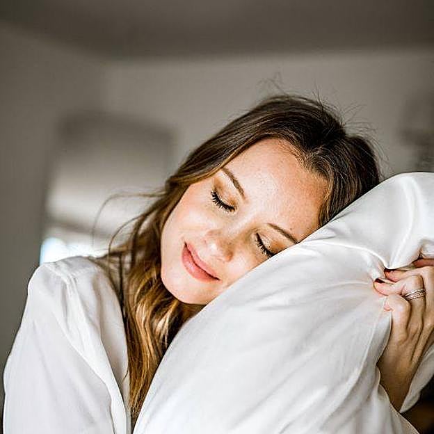 Mujer durmiendo sobre almohada de seda