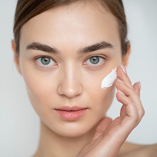 Mujer aplicándose crema en el rostro. 