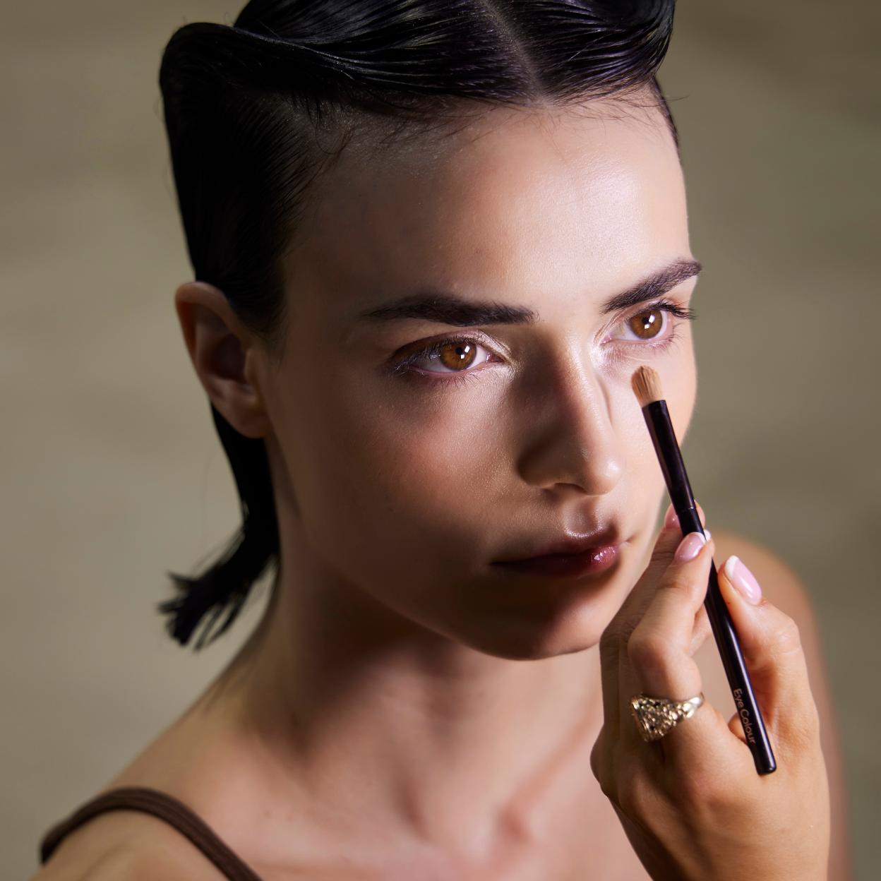 Una modelo aplicándose el corrector en las ojeras.