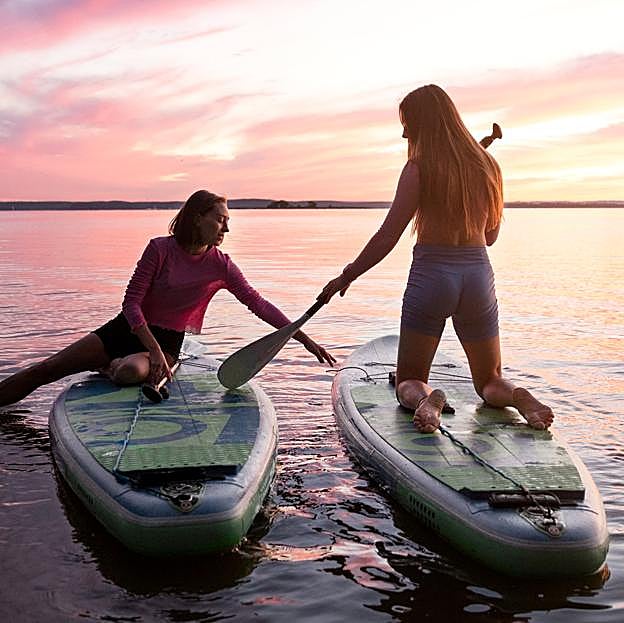 Dos mujeres practicando paddle surf. 