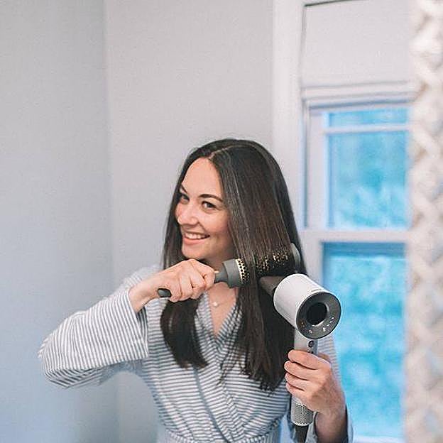 Mujer usando secador con cepillo
