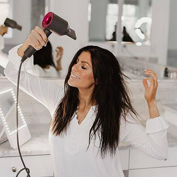 Mujer dando uso correcto del secador de pelo