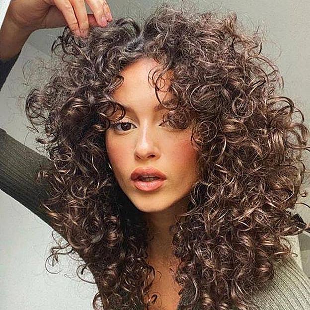 Influencer con corte mariposa en pelo rizado tendencia