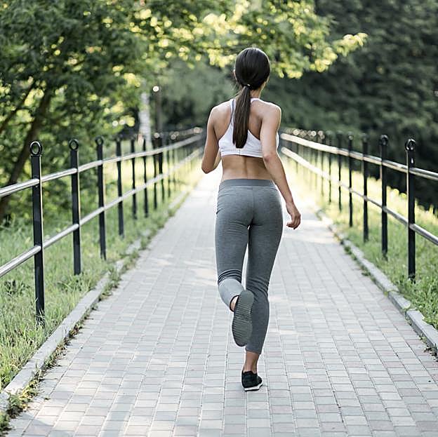 Mujer de espaldas andando por un camino. 