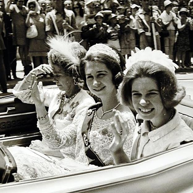 La reina Federica se tapa la cara para evitar el sol durante un paseo en descapotable con sus hijas, Sofia e Irene de Grecia.