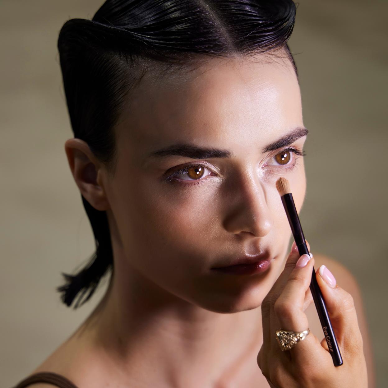 Una mujer maquillando a otra en la Semana de la Moda.