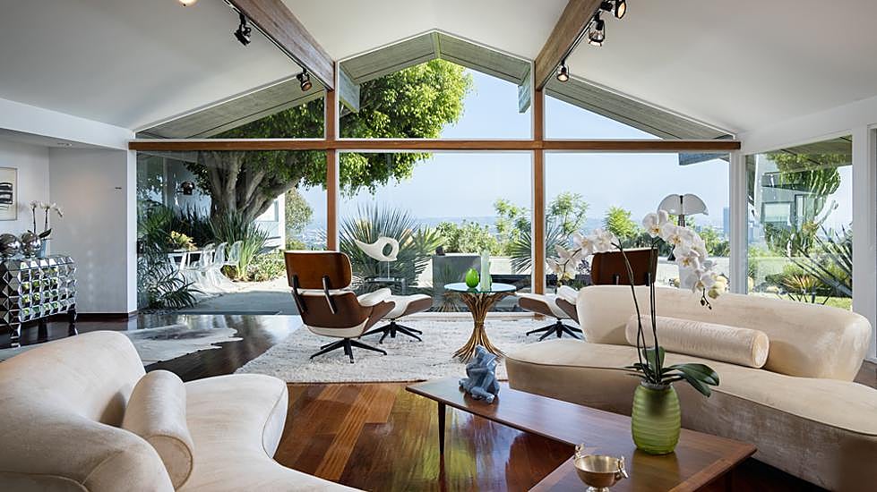 La gran sala de estar, con una pared acristalada, da al jardín. Un par de sillones y otomanas Lounge, de los Eames, sirven para disfrutar de las vistas. Los sofás son de Vladimir Kagan; sobre la mesa, escultura japonesa de los años 60.