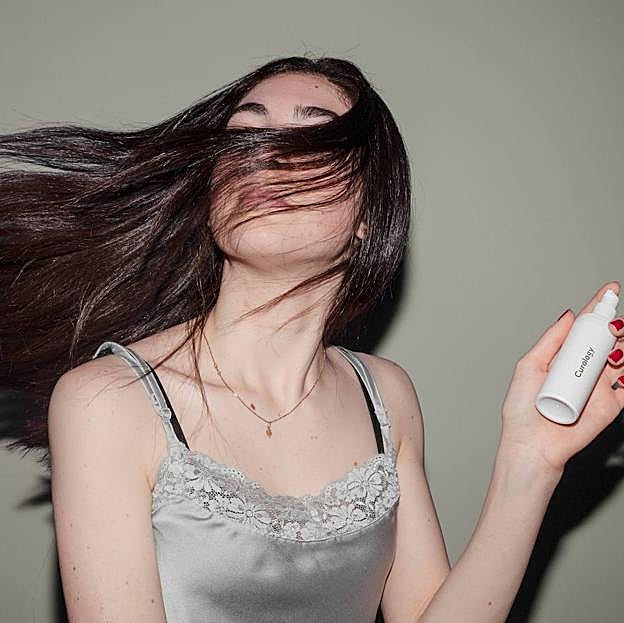 Mujer usando protector de calor para el pelo