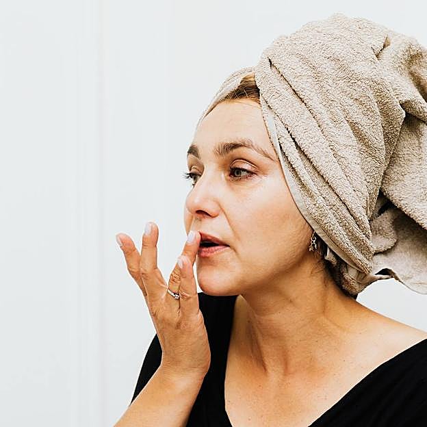 Mujer usando crema para suavizar las líneas de expresión del labio superior