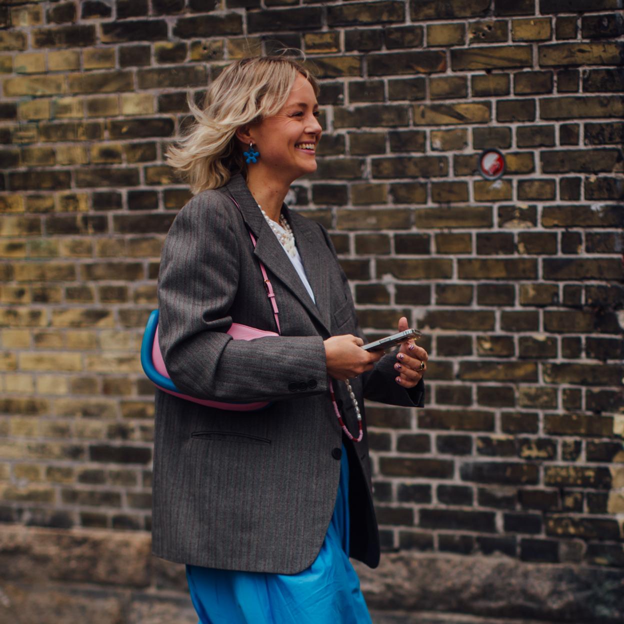 Una mujer caminando con el móvil en la mano.
