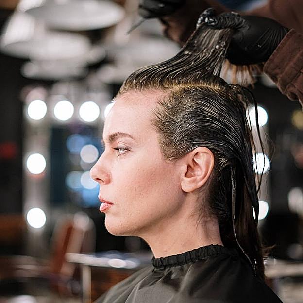 Estilista aplicando tinte con barros