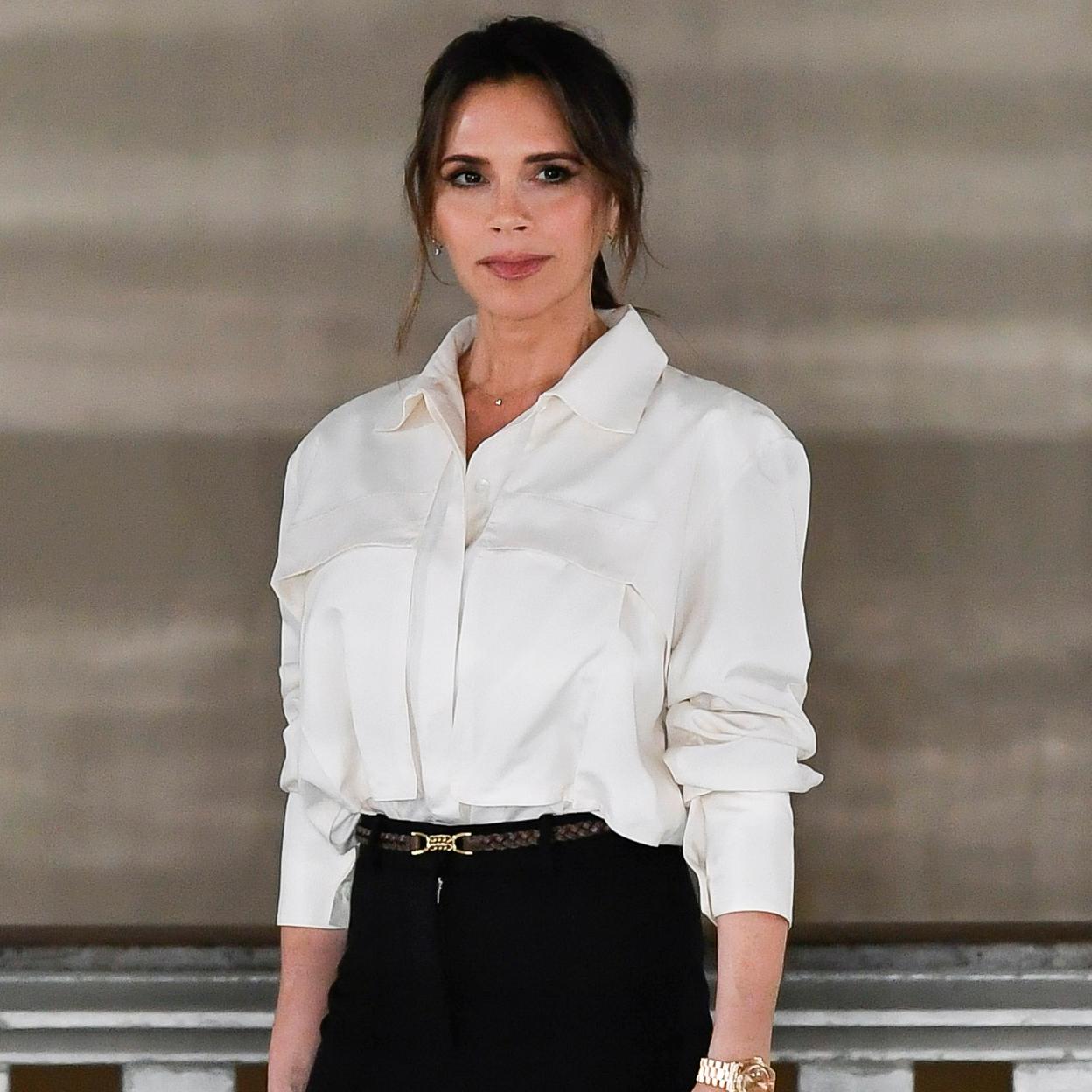 Victoria Beckham con camisa blanca y pantalón negro. 