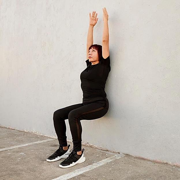 Mujer realizando el ejercicio de pilates en la pared que afina la cintura. 