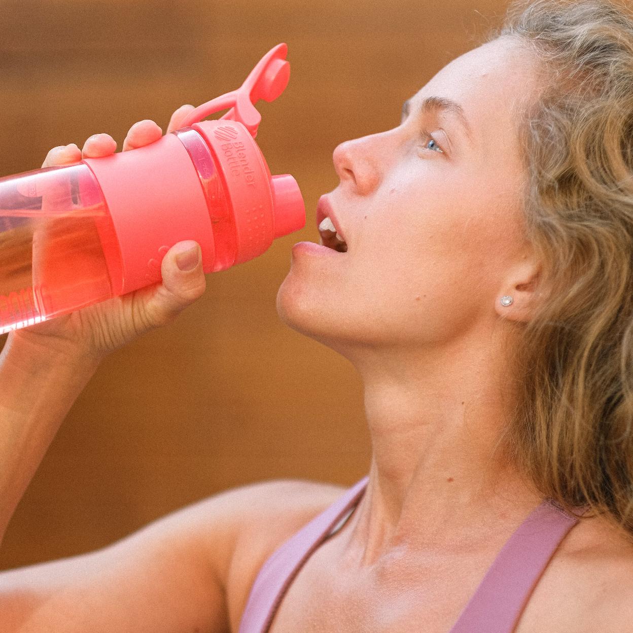 Mujer hidratándose después de hacer ejercicio. 
