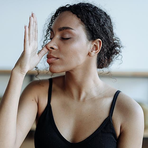 Mujer practicando la respiración alterna para calmar el estrés. 