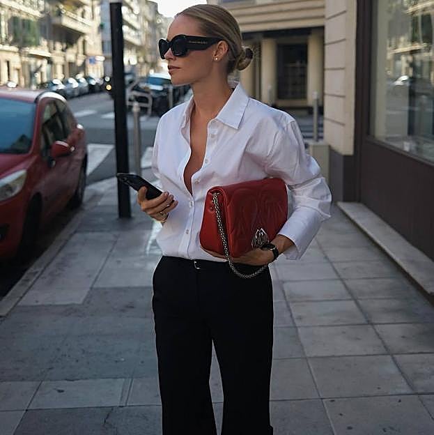 Look con camisa blanca, pantalones de vestir negros y la tendencia pop off red con bolso rojo