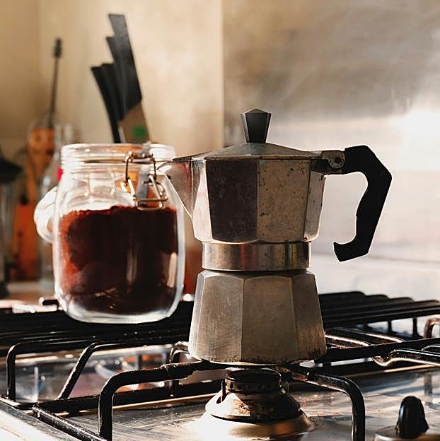La cafetera se calienta a temperatura media-baja y, a diferencia de la imagen, con la tapa levantada.