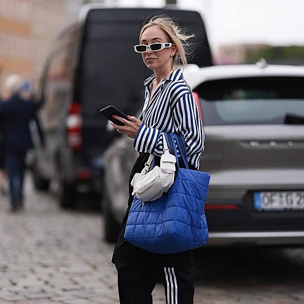 Influencer con look de pantalones Adidas de chándal, camisa de oficina y botas