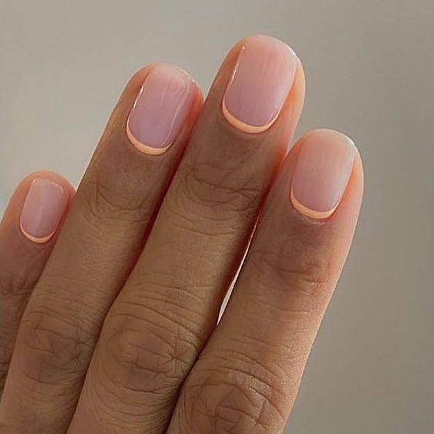 Manicura francesa invertida con la tendencia de uñas peach fuzz en tono melocotón