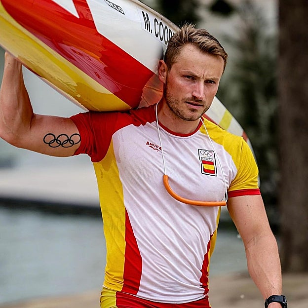 Marcus Cooper, kayak al hombro, con los aros olímpicos tatuados. 