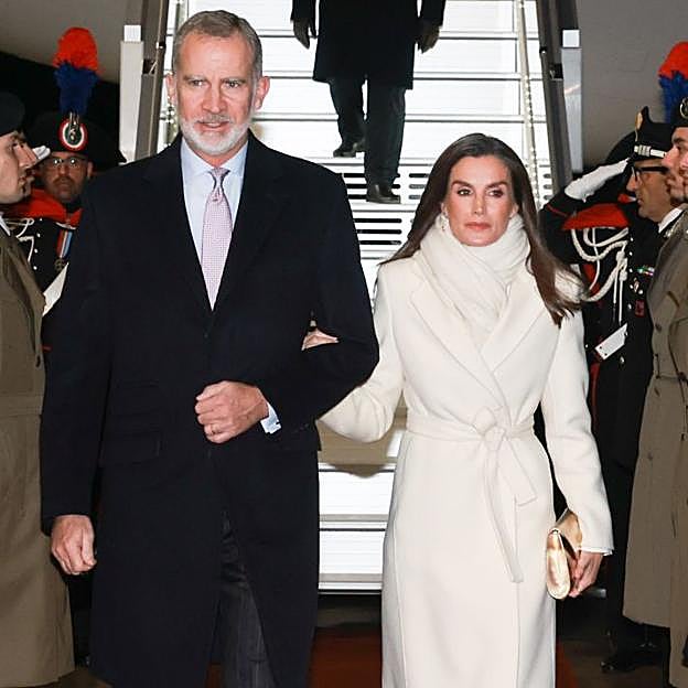 La reina Letizia sorprende en su llegada a Italia con un impoluto look blanco: abrigo largo y zapatos metalizados