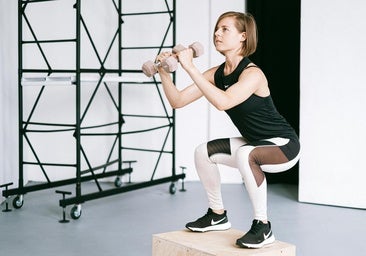 Mujer realizando sentadillas con peso.