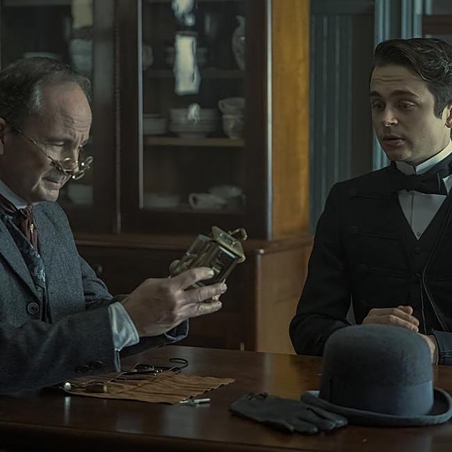 Ben Ahlers como Trotter, presentando su creación, un reloj con alarma que no precisa mantenimiento.