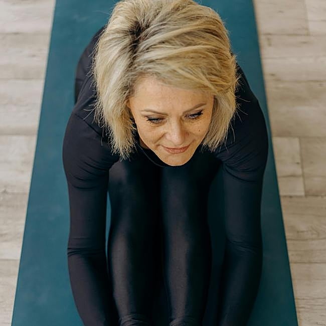 Mujer practicando yoga en casa.
