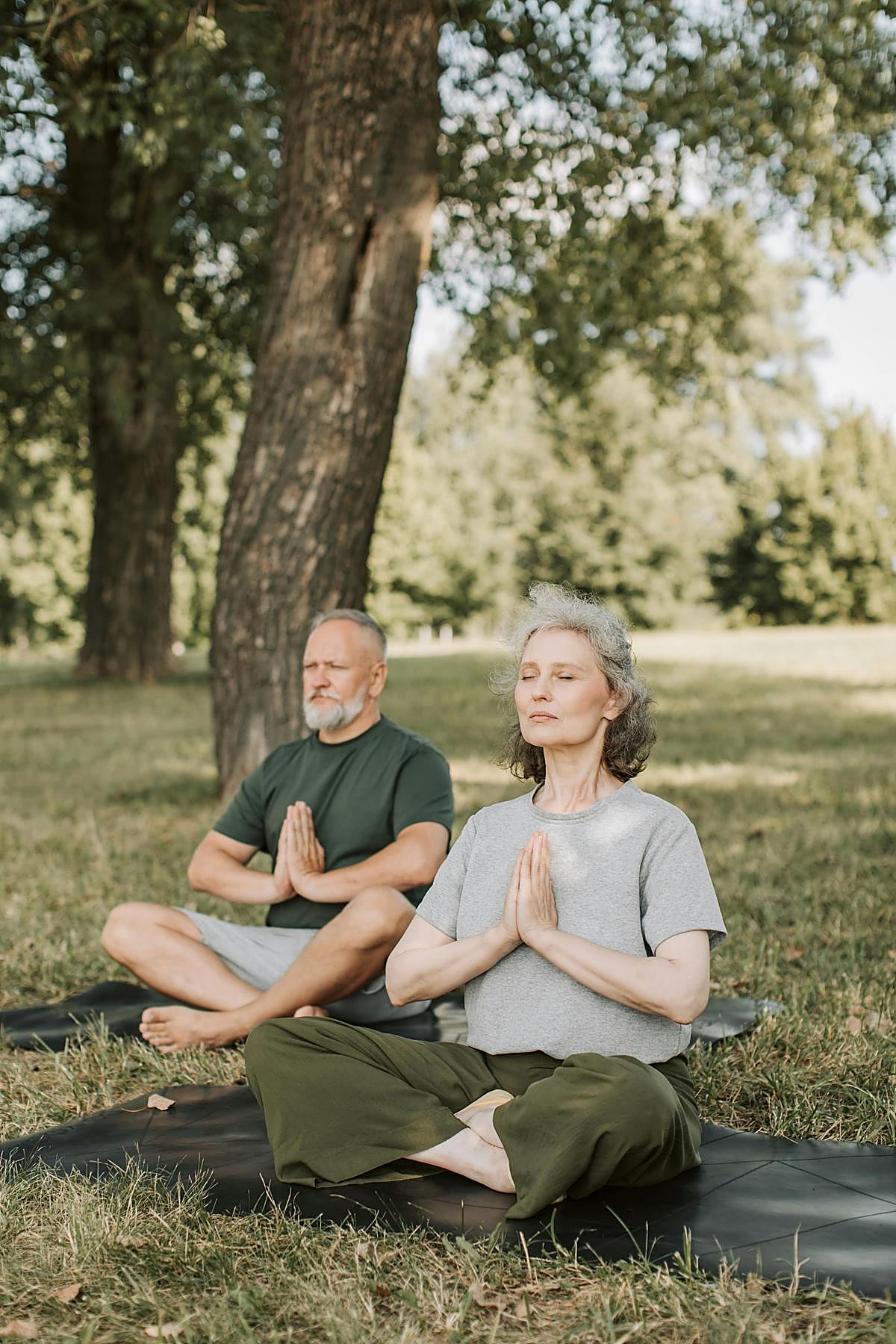 Pareja haciendo postura de yoga al aire libre.