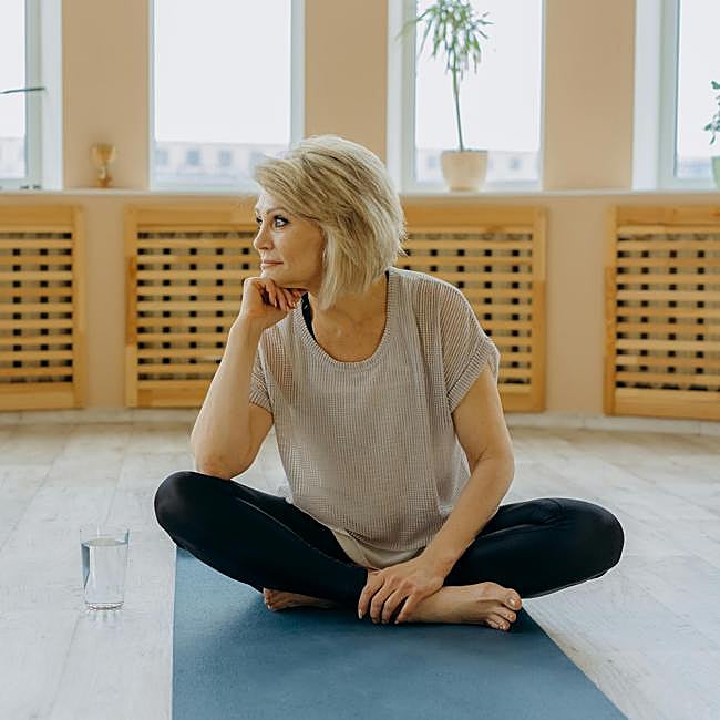 Mujer practicando yoga sobre esterilla.