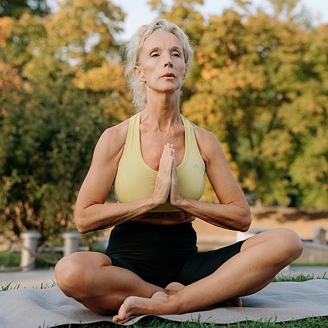 Mujer practicando yoga al aire libre.